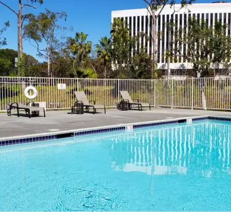 Outdoor swimming pool with lounge chairs and building behind.