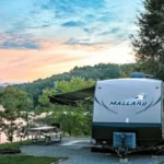 Travel trailer by lakeside at sunset.