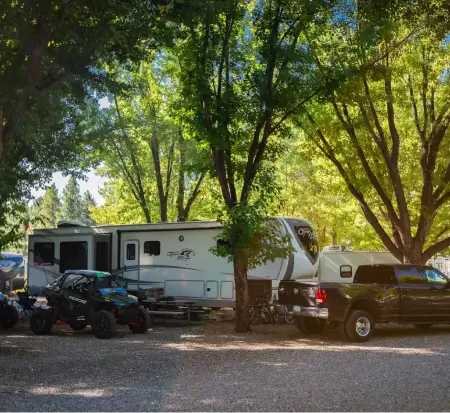 RV and truck parked in wooded campground.