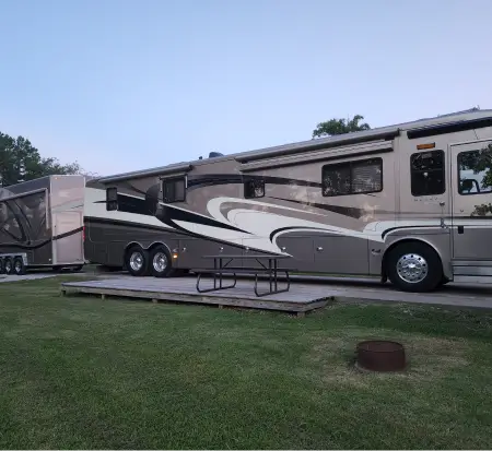 Class A motorhome with attached trailer parked outdoors.