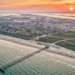 Aerial view of coastal town at sunset with pier.