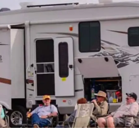 People relaxing by an RV camper.