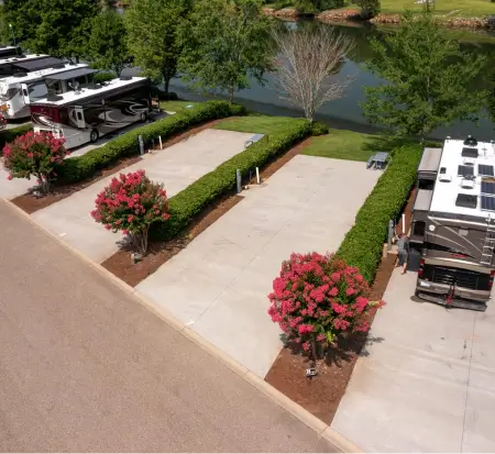 RV park with flowering shrubs and lake view.