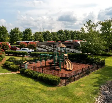 Outdoor playground with slides and greenery on sunny day.